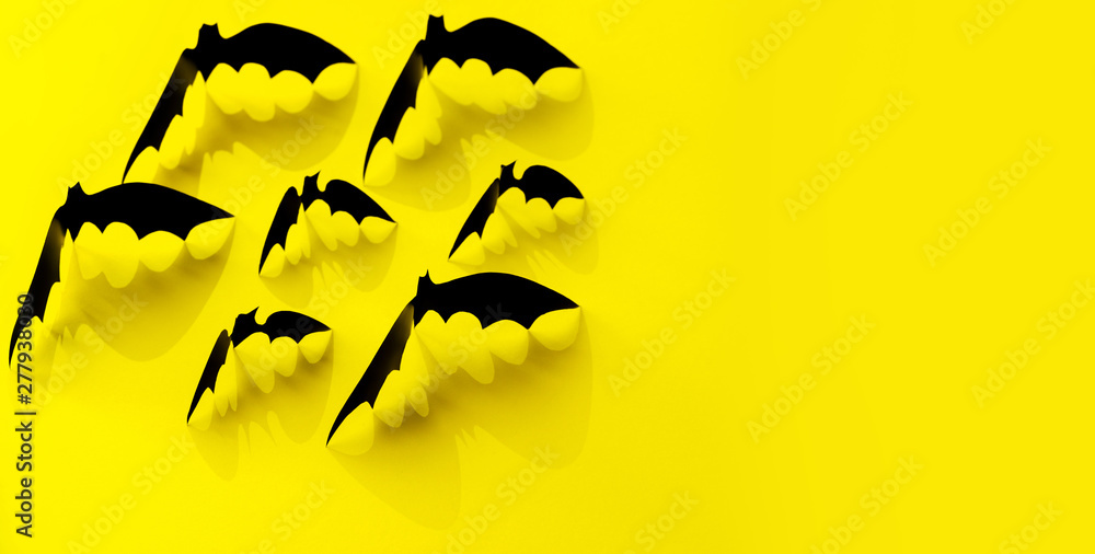 Minimalistic Paper bat pattern with falling shadow on yellow background. Halloween decorations banner. Halloween concept. Flat lay, top view, copy space. Minimalistic Paper bat pattern with falling shadow on yellow background. Halloween decorations banner. Halloween concept. Flat lay, top view, copy space.