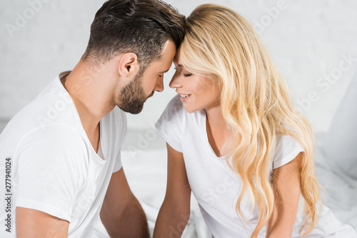beautiful couple in white t-shirts touching with foreheads at home © LIGHTFIELD STUDIOS
