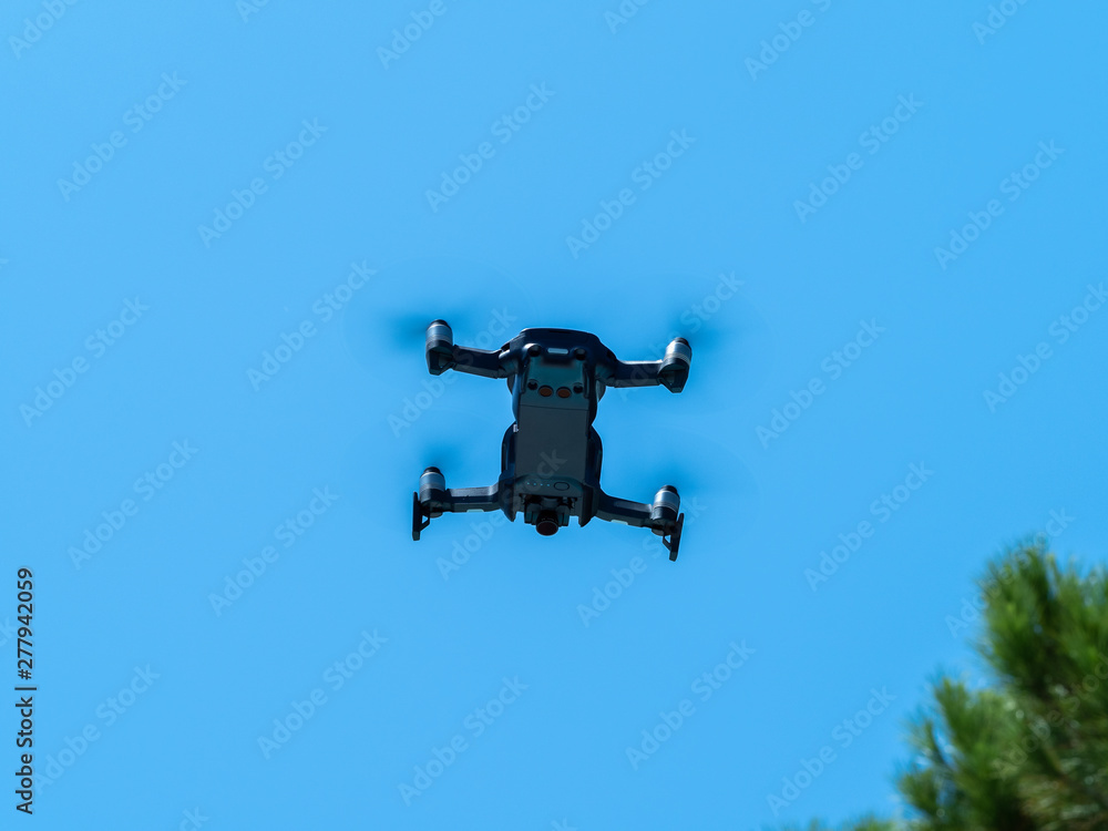 Image of a drone under the blue sky in full flight. Image of a drone under the blue sky in full flight.