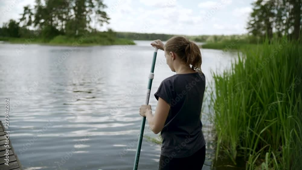 Young woman paddler is launching a stand up paddleboard on lake. Slow motion Young woman paddler is launching a stand up paddleboard on lake. Slow motion