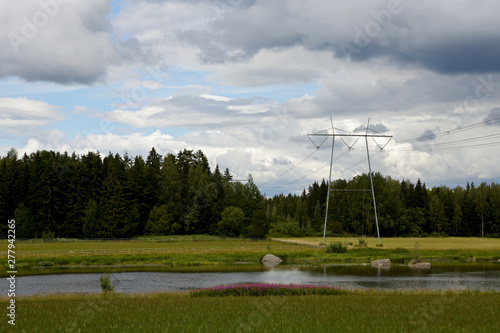 A power line over Kokemaki-river and forests on a cloudy summer evening