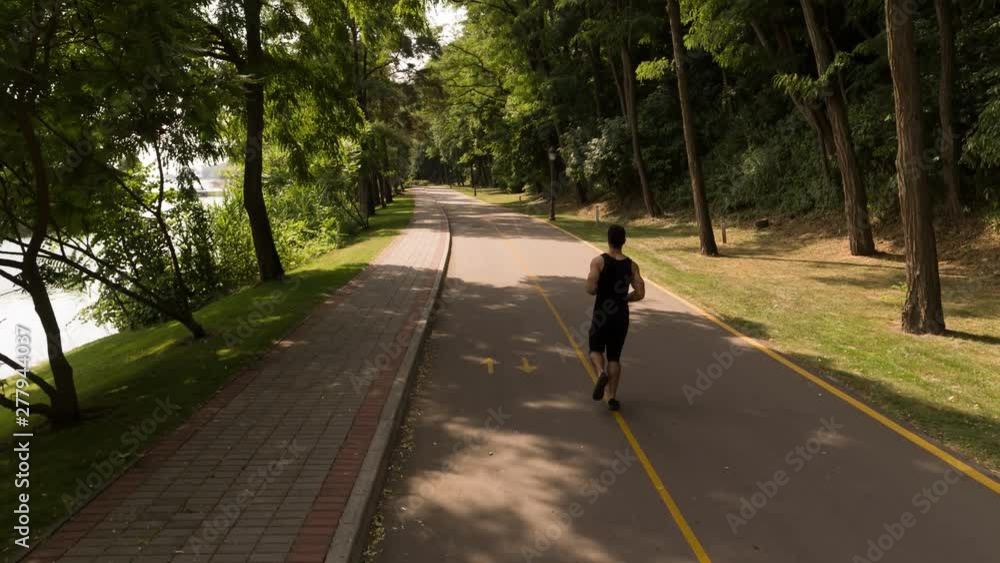Man running in Park sunny day Follow shot Back view video. Sportsman Runner Athlete training Man running in Park sunny day Follow shot Back view video. Sportsman Runner Athlete training