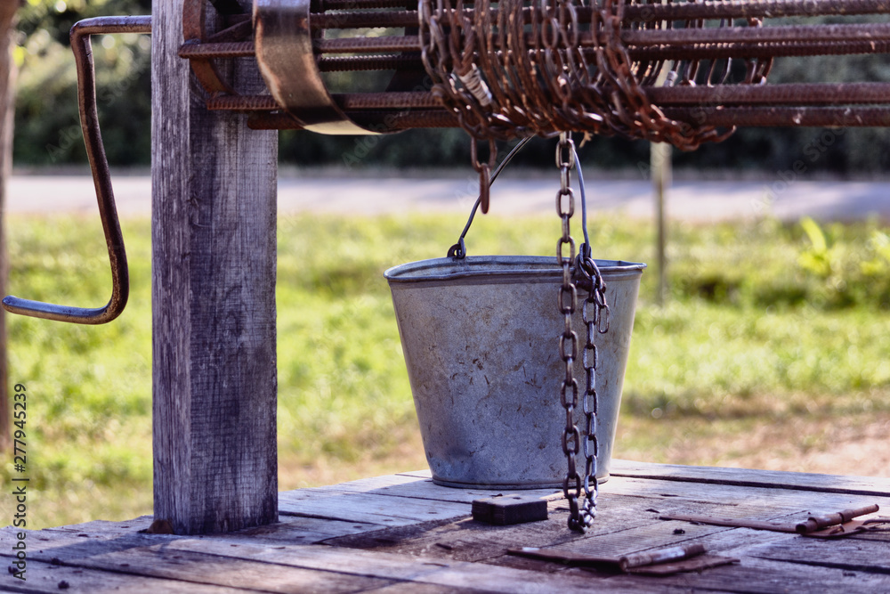 Old wooden well with a rusty collar, drum, chain and bucket. Old wooden well with a rusty collar, drum, chain and bucket.