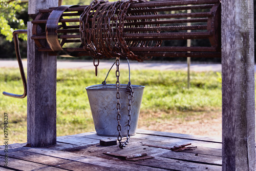 Old wooden well with a rusty collar, drum, chain and bucket. photo