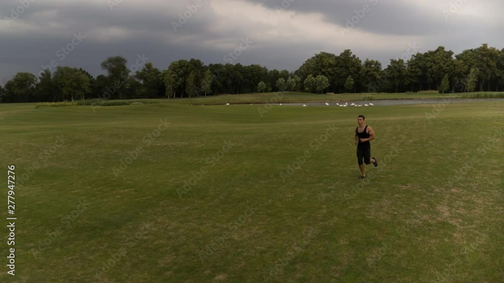 Man running on green meadow Follow camera flyby shot video. Sportsman Runner Athlete training Man running on green meadow Follow camera flyby shot video. Sportsman Runner Athlete training