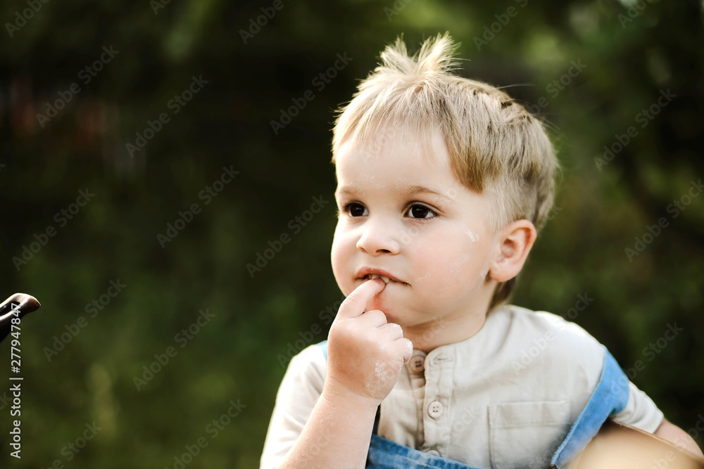 Boy with finger in mouth looking away while sitting in backyard Boy with finger in mouth looking away while sitting in backyard