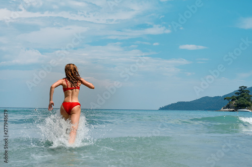 beautiful young woman running in the sea.