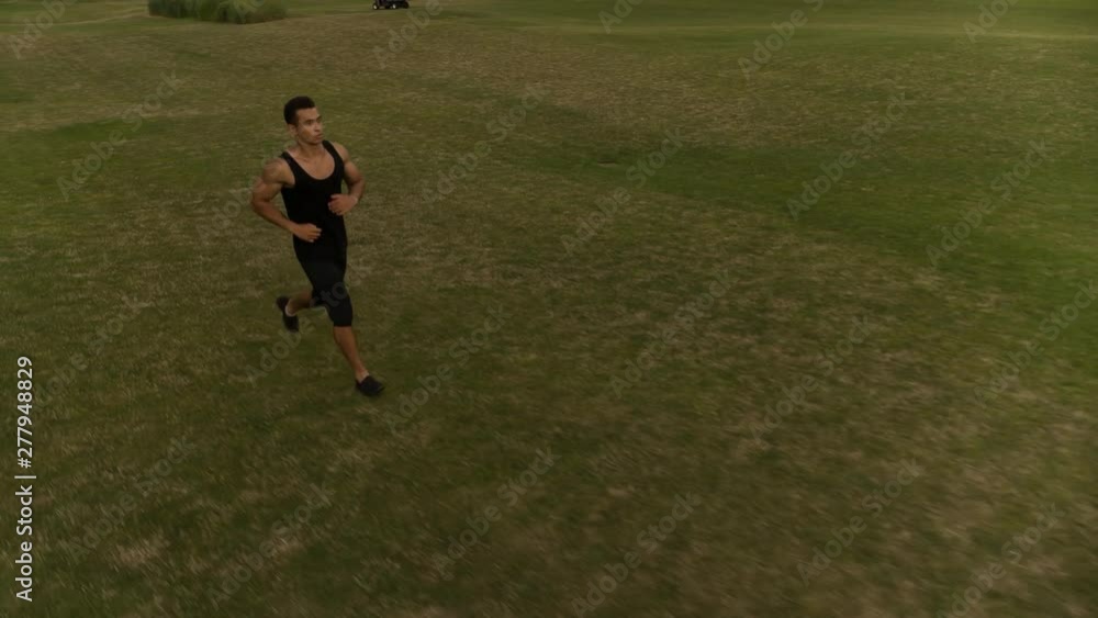 Man running on green meadow Follow camera flyby shot video. Sportsman Runner Athlete training Man running on green meadow Follow camera flyby shot video. Sportsman Runner Athlete training