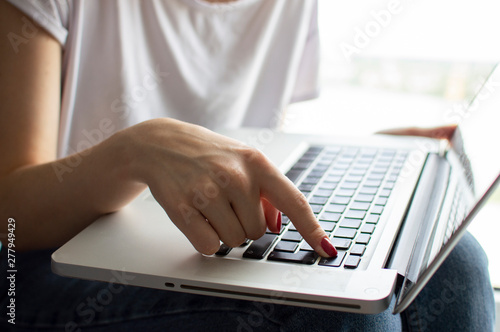girl's hand typing on a laptop keyboard, she presses Enter key, moment of confirmation, close-up