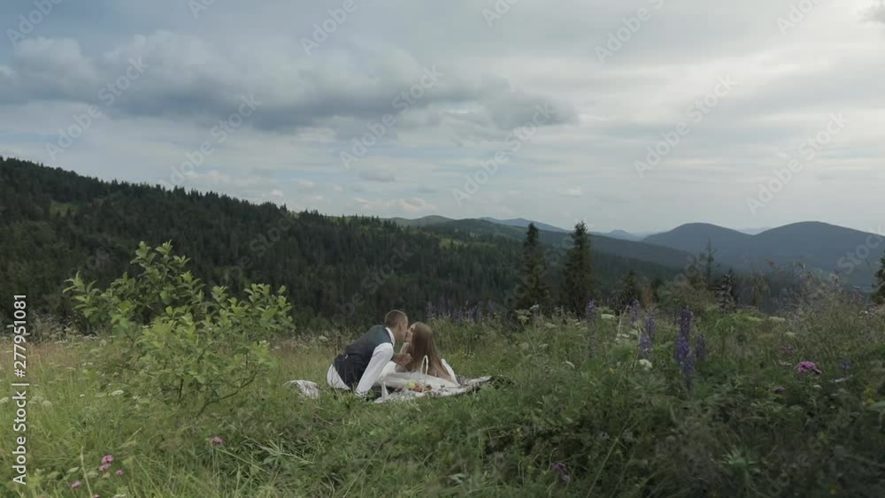 Groom with bride having a picnic on a mountain hills. Wedding couple. Family Groom with bride having a picnic on a mountain hills. Wedding couple. Family