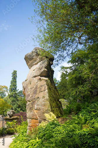 Large Rock Boulder against a natural blue sky surrounded by lush green trees in Derbyshire, UK