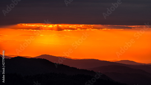 Fototapeta Naklejka Na Ścianę i Meble -  A wonderful sunset in the mountains. Orange sky and dark silhouettes of mountains. Carpathian Mountains landscape. Bieszczady. Poland