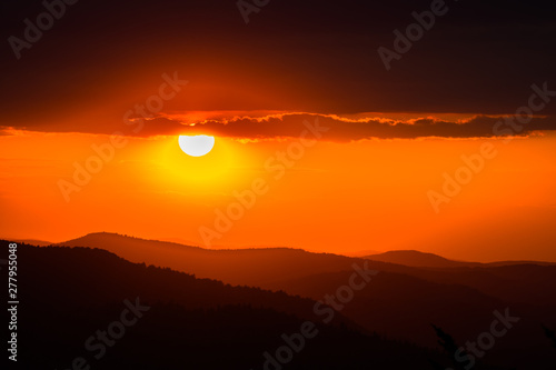 A wonderful sunset in the mountains. Orange sky and dark silhouettes of mountains. Carpathian Mountains landscape. Bieszczady. Poland