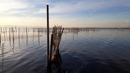 Panoramic view of Lake Albufera in Valencia, at sunset, with calm water, near fishing nets. © Joaquin Corbalan