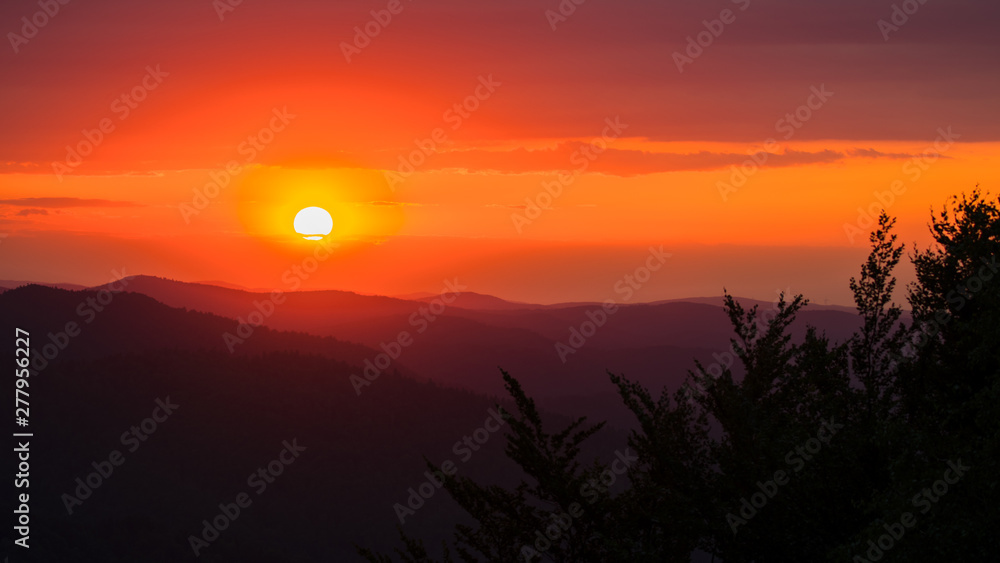 Naklejka premium A wonderful sunset in the mountains. Orange sky and dark silhouettes of mountains. Carpathian Mountains landscape. Bieszczady. Poland
