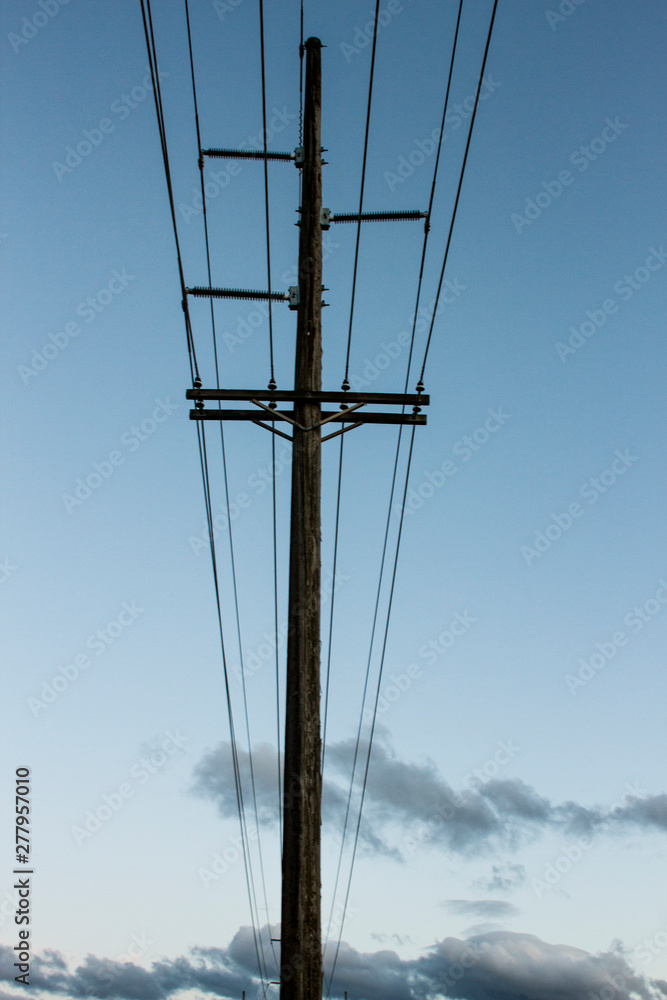 Electricity runs through power lines on a power pole at twilight Electricity runs through power lines on a power pole at twilight
