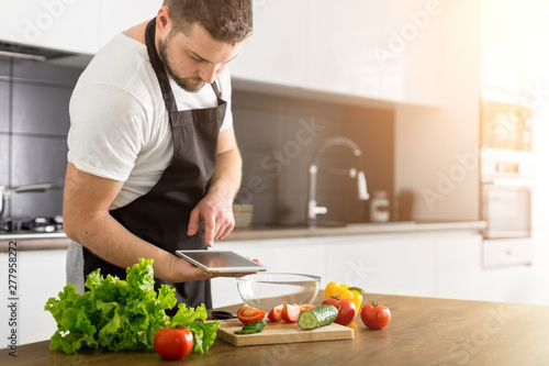 Young trendy man cooking healthy food in the morning