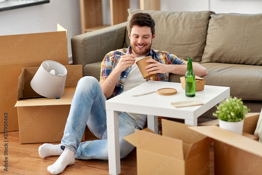 moving, consumption and people concept - smiling man eating takeaway food for lunch at new home moving, consumption and people concept - smiling man eating takeaway food for lunch at new home