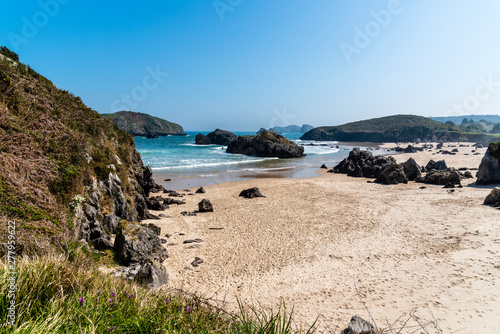 Scenic view of sand beach with rocks against blue sky photo