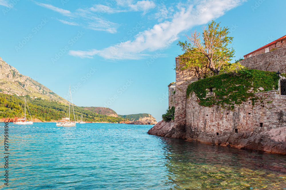 Picturesque summer seascape, part of Sveti Stefan island and luxury yachts in adriatic sea, Montenegro