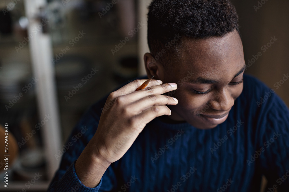 High angle view of smiling teenage boy holding pencil while studying at home High angle view of smiling teenage boy holding pencil while studying at home