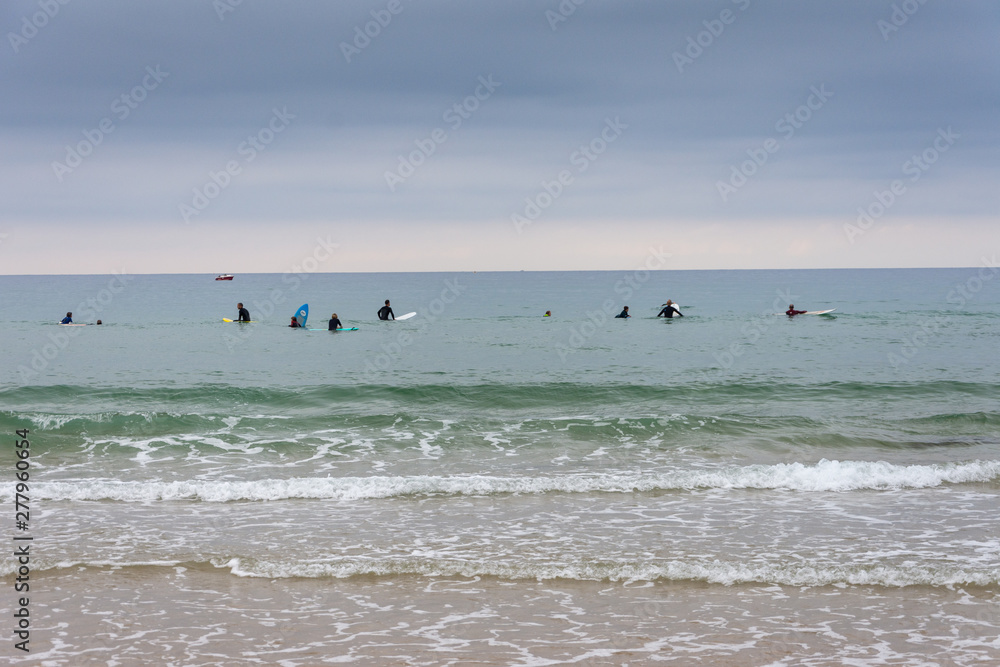 View from the beach of a group of surfers waiting for the waves, a cloudy afternoon in Cantabria, Spain, Europe