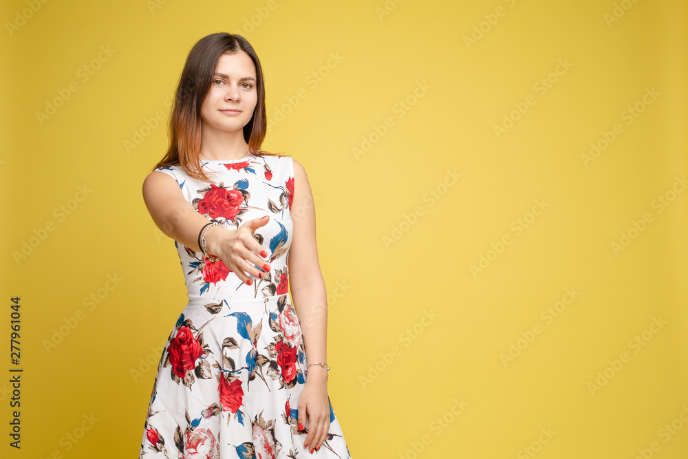 Young beautiful girl in colorful clothes posing at camera. Brunette pretty lady in dress with big red flowers holding her hand up gesturing by it. Attractive cute woman wearing many bracelets on arms. Young beautiful girl in colorful clothes posing at camera. Brunette pretty lady in dress with big red flowers holding her hand up gesturing by it. Attractive cute woman wearing many bracelets on arms.