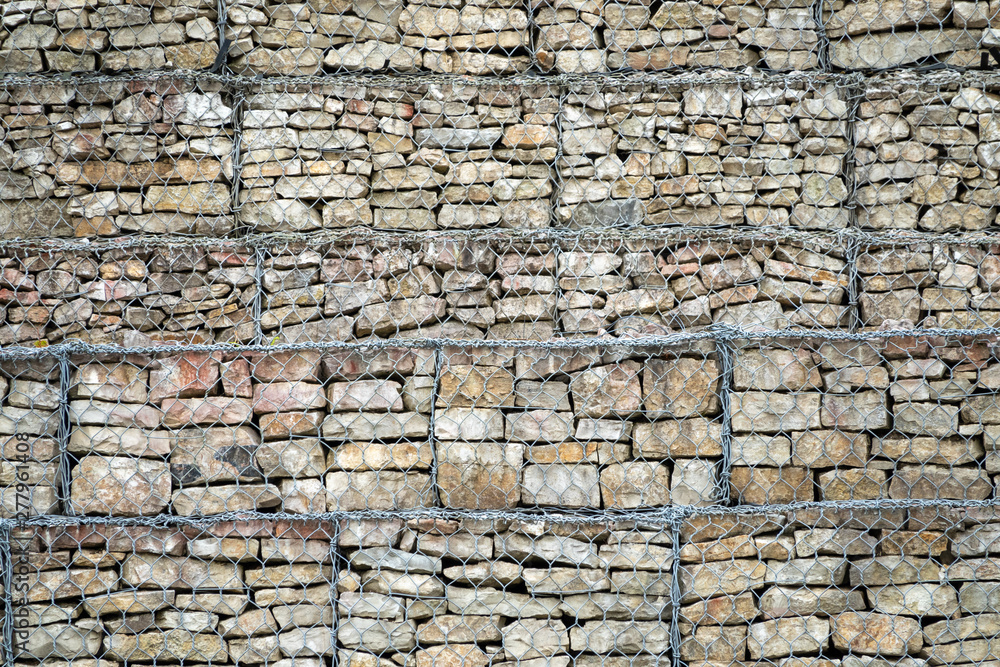 Gabion Wall From Rocks And Stones In Metal Wire Box. Fence of stones in the grid. Protective stone wall in the grid.