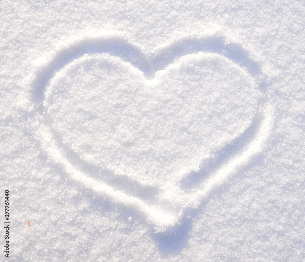 Symbol of heart on the background of fresh snow texture. Merry Christmas or Valentine's Day Concept. Copy space for your text.