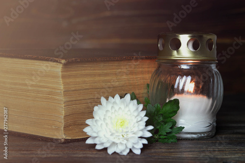 White memorial candle, chrysanthemum flower and book photo