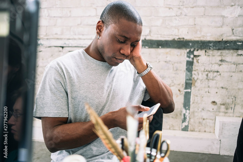 Young male hacker using smart phone while sitting at creative workplace photo