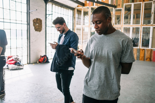 Confident young businessman using smart phone while walking by colleague at creative workplace photo