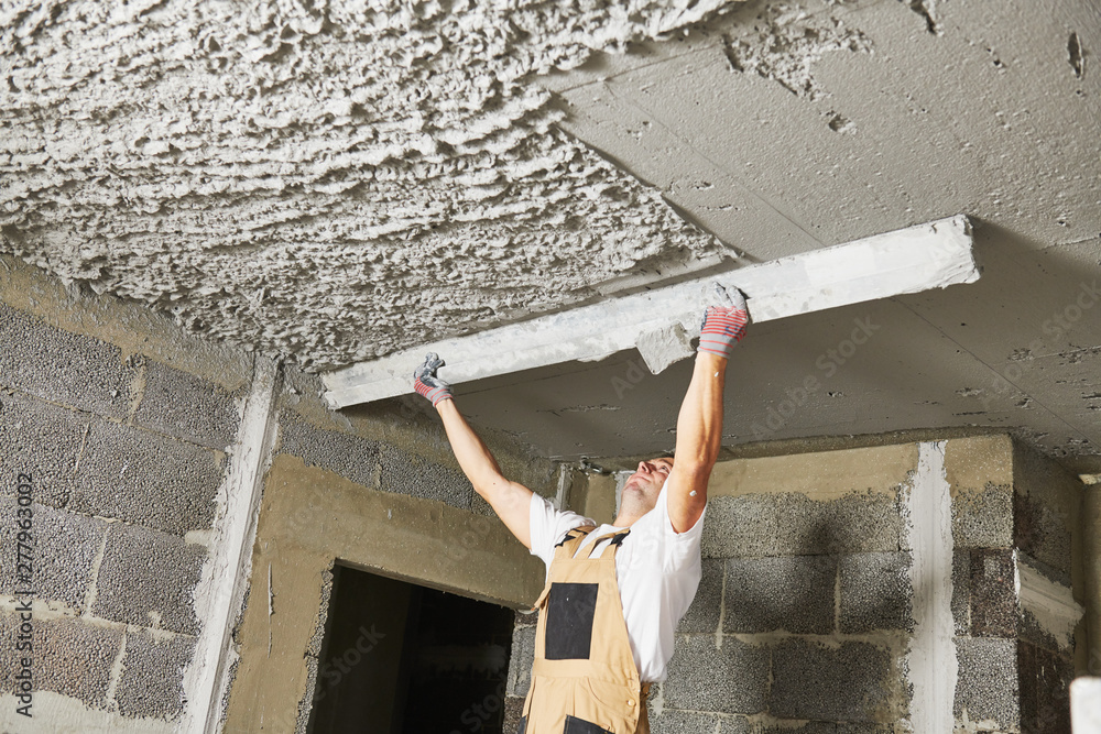 Plasterer smoothing plaster mortar on ceiling with screeder foto de