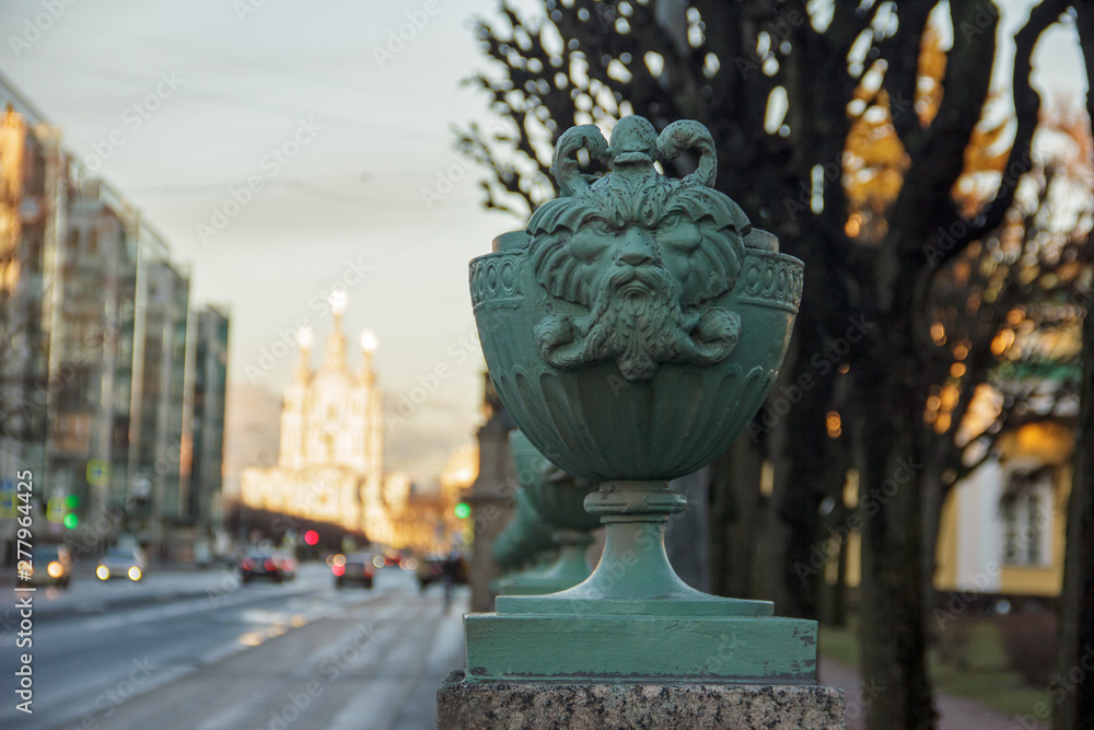 Maskaron from the fence of the Tauride Palace (in which the Inter-Parliamentary Assembly of the CIS member states is located) against the background of the Smolny Cathedral
