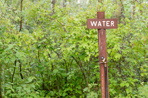 a wooden water sign and water tap in outdoor park 