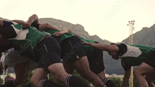 Rugby players doing a scrum at the field. Rugby players fight for the ball on professional rugby stadium.  photo