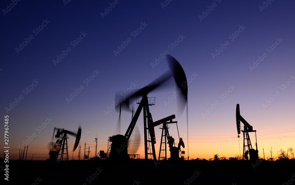 The pumping unit is working, silhouetted against the setting sun The pumping unit is working, silhouetted against the setting sun