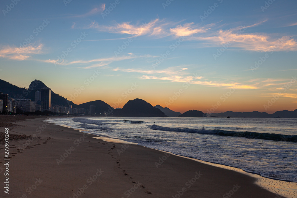 Smooth sand beach left by the ocean waves at early morning sunrise on Copacabana in Rio de Janeiro with the Sugarloaf mountain in the background Smooth sand beach left by the ocean waves at early morning sunrise on Copacabana in Rio de Janeiro with the Sugarloaf mountain in the background