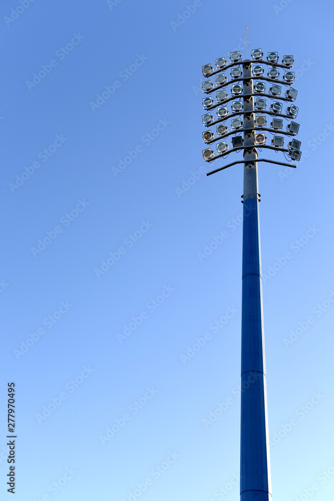 Sports stadium light tower during the day, set against a blue sky. Sports stadium light tower during the day, set against a blue sky.