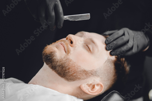 Barbershop. Hairdressers barber hair and beard with razor in salon