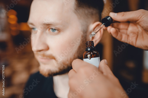 Barber does oil for care and growth of beard, barbershop