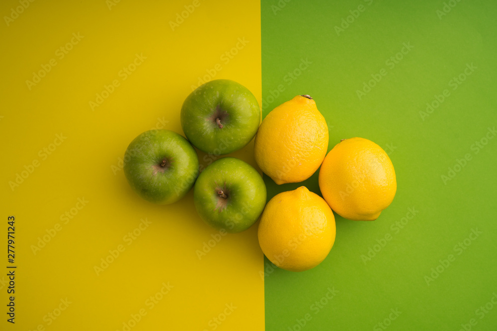 Green apple and lemon on green and yellow paper background Green apple and lemon on green and yellow paper background