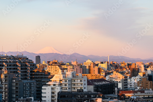 Colorful sunset in Tokyo, Japan Shinjuku cityscape with silhouette of Mount Fuji and golden sunlight, apartment buildings and mountains photo