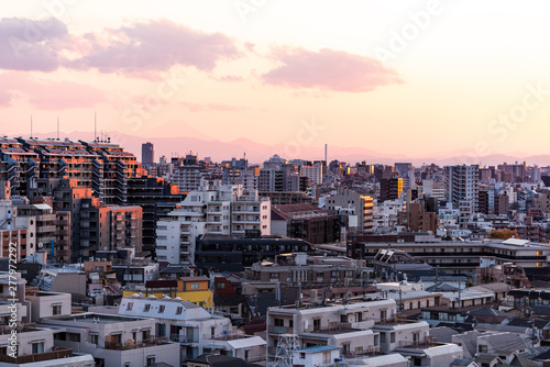 Shinjuku cityscape in Tokyo, Japan at sunset with view of Mount Fuji and golden sunlight with apartment buildings and mountains