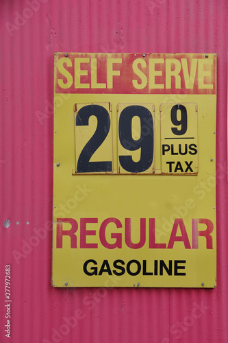 An old weathered sign at a defunct gas station showing the price for regular of decades ago