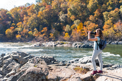 Young woman photographer taking photo picture with camera of view of Potomac river in Great Falls with autumn colorful foliage in Maryland photo