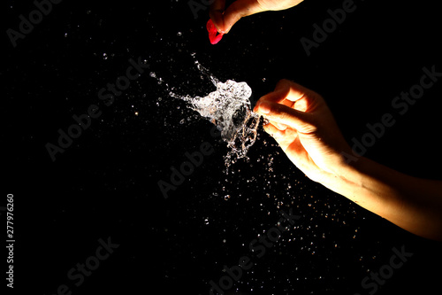 Popping the water balloon on black background © taffpixture