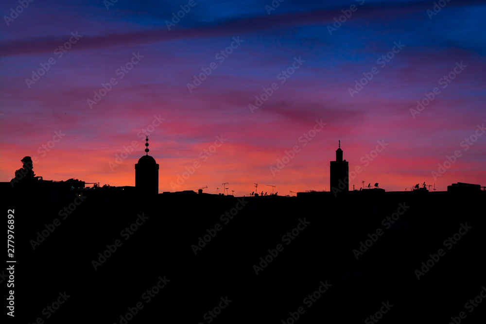 Violet sunset above moroccan city Fes with silhouette of minarets