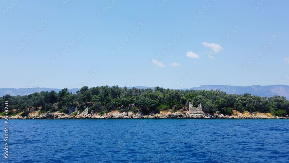 A tracking shot of idyllic Aegean islands in the summer, from Gulf of Gokova. Stone ruins from Roman times can also be seen on the island. Shot and presented at 60 fps. A tracking shot of idyllic Aegean islands in the summer, from Gulf of Gokova. Stone ruins from Roman times can also be seen on the island. Shot and presented at 60 fps.