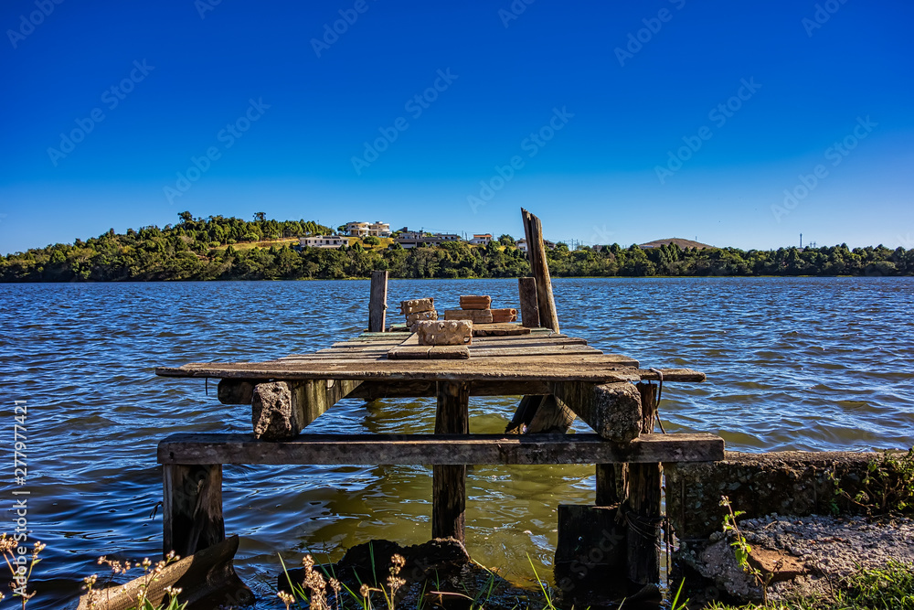 Abandoned wooden deck on dam in sunny morning with blue sky